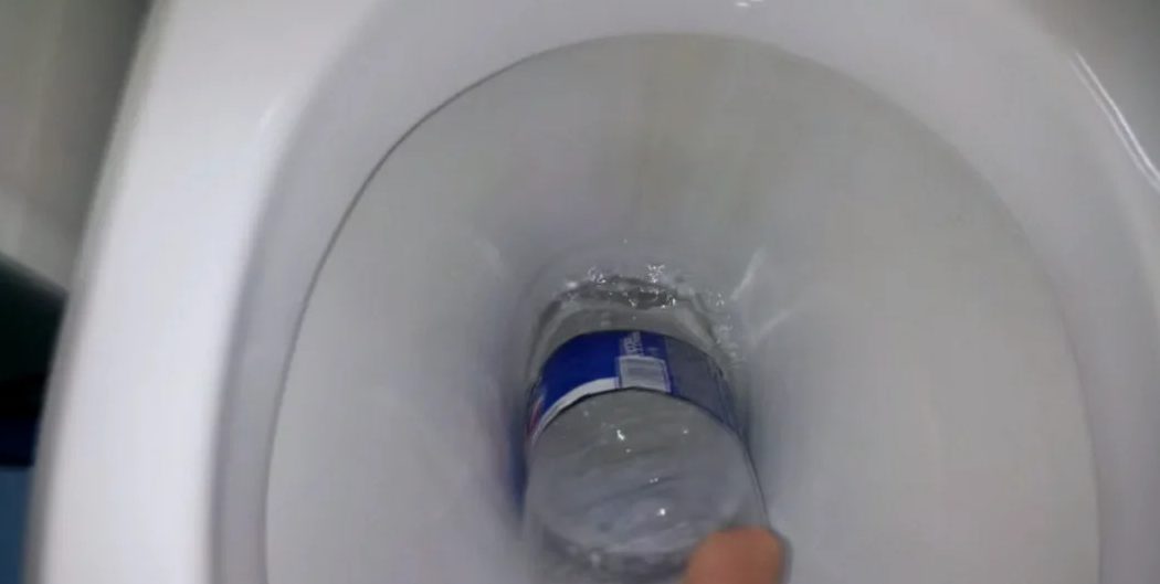 καθαρίζοντας το μπολ τουαλέτας με ένα πλαστικό μπουκάλι